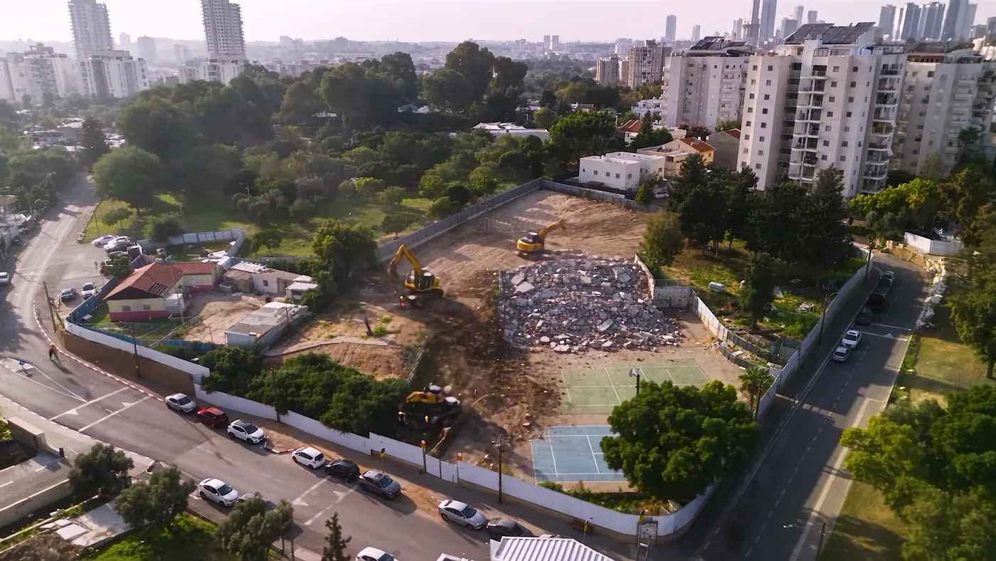המבנה הישן במגרש בשלב הפינוי, עם ערמת הריסות ומחפרונים